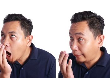Funny Asian man check his own mouth smell isolated on white